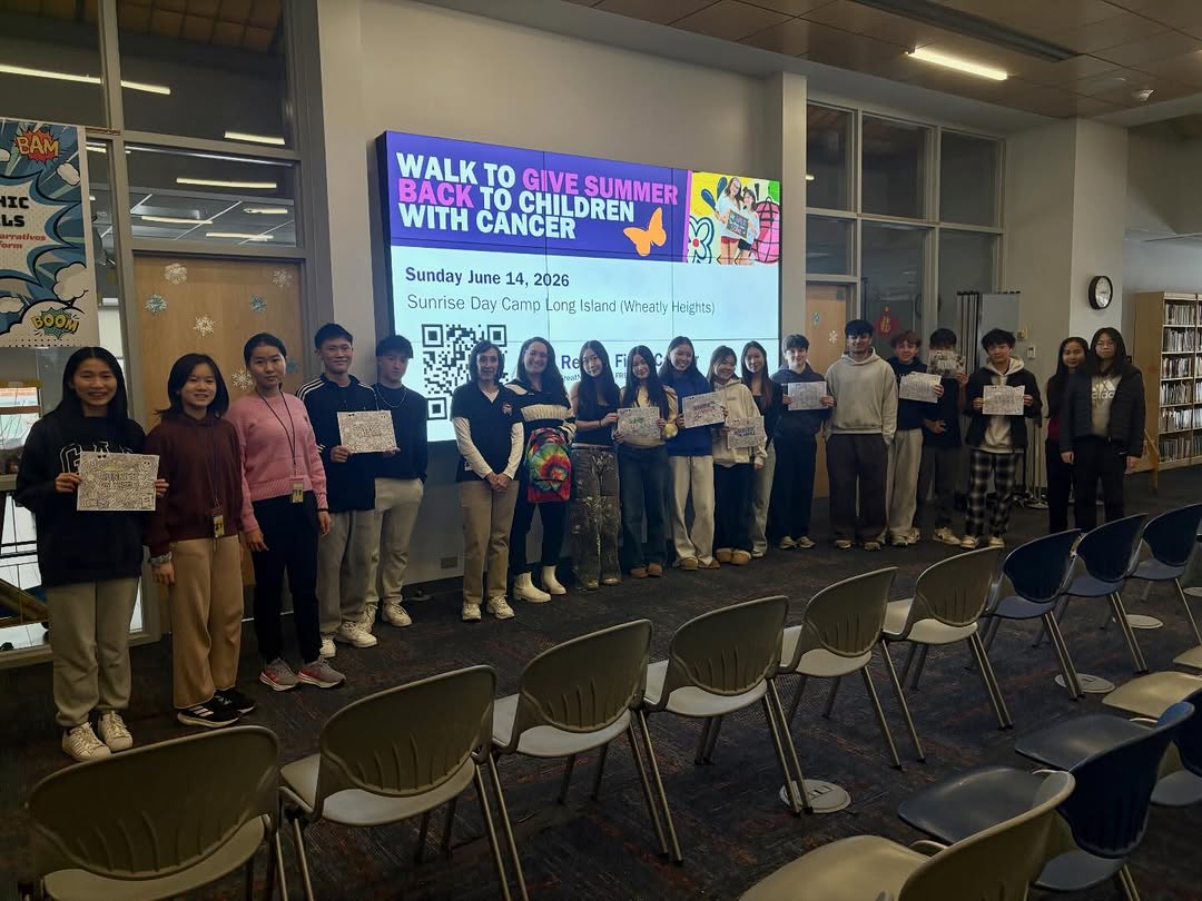 Rebels Fight Cancer members at the GNS library hosting the Sunrise Association, with a slide reading 'Walk to Give Summer Back to Children with Cancer — Sunday June 14, 2026'